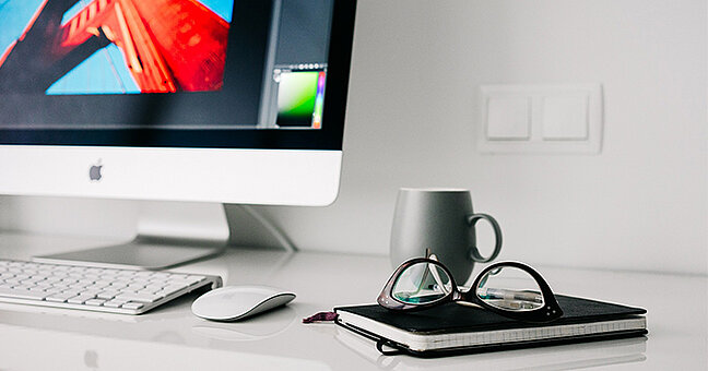 Arbeitsplatz mit iMac, iPad und Tasse