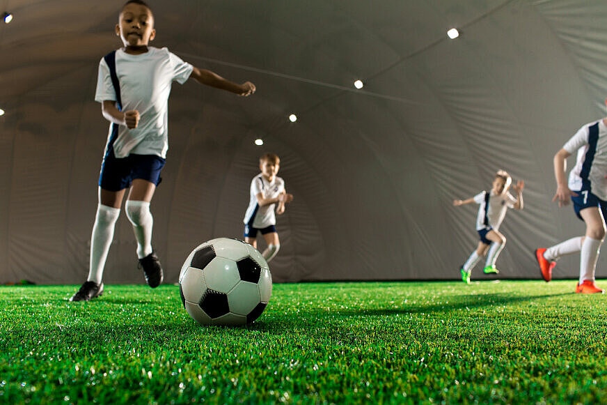 Kinder spielen in einer Soccerhalle Fußball