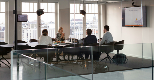 4 Personen bei einer Konferenz am langen Tisch